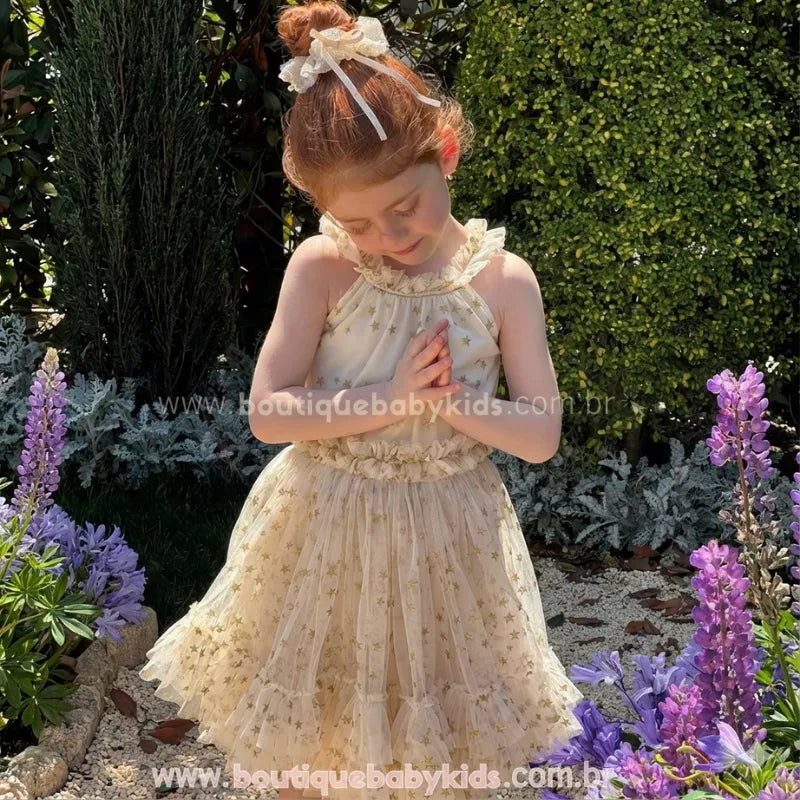 Menina posando de frente com o Vestido Infantil Brilho das Estrelas. Destaque para o detalhe da gola com babadinhos e o tecido leve na cor creme com brilho.