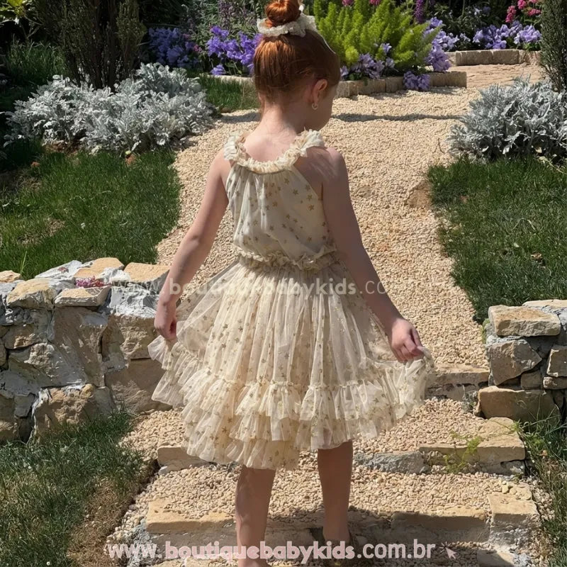 Vista traseira do Vestido Infantil Brilho das Estrelas no corpo. Mostra o decote estilo nadador com babados nas alças e o caimento volumoso da saia de tule nas costas.