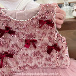 Detalhe aproximado do tecido com brilho e aplicação de pérolas no decote do vestido infantil.