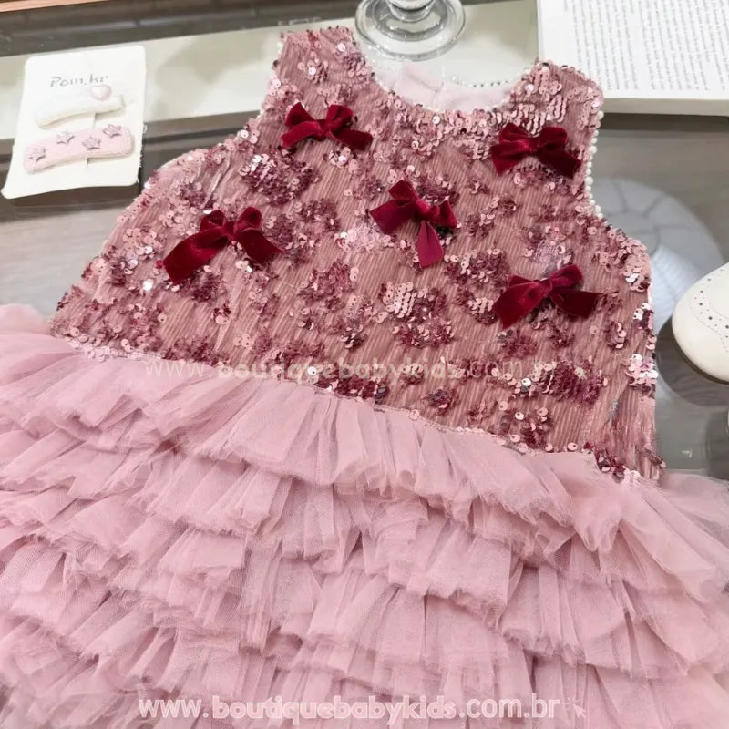 Detalhe do busto do vestido infantil rosé com bordado de lantejoulas e laços decorativos de veludo bordô.