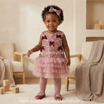 Menina vestindo o Vestido Infantil Doce Elegância Rosé com saia de tule e tiara de laço em cenário clean.