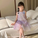 Menina sentada usando vestido de Sereia roxo com brilho, demonstrando o conforto e o caimento da saia de tule para festas.