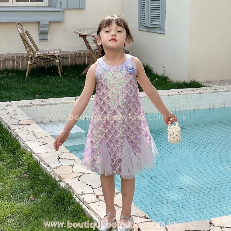 Menina usando Vestido Infantil Encanto da Sereia na cor lilás com lantejoulas brilhantes que imitam escamas, em cenário externo.