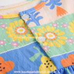 Close dos botões frontais do vestido com detalhe das flores amarelas estampadas. - Boutique Baby Kids