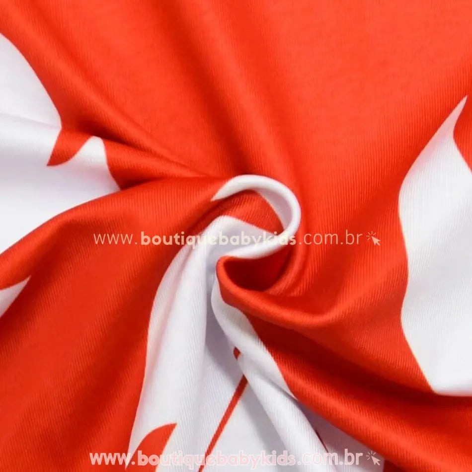 Detalhe do tecido em poliéster do vestido infantil Lilo, com estampa de folhas brancas sobre fundo vermelho.