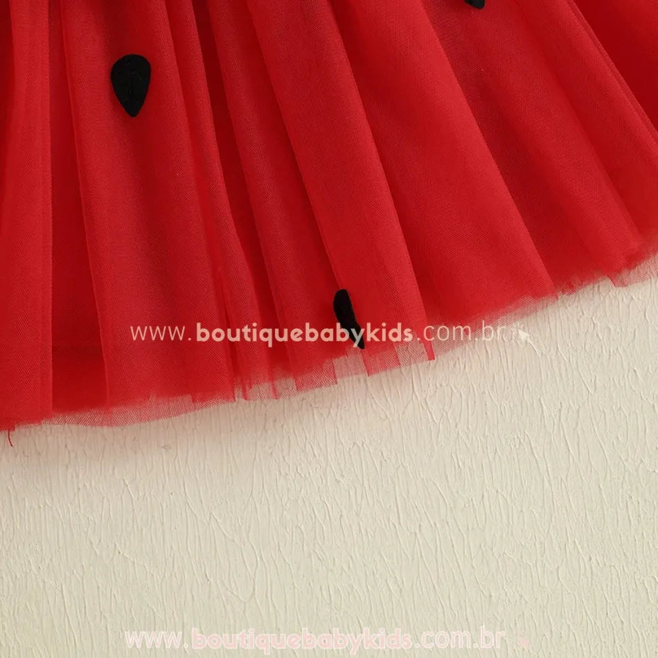 Detalhe da saia de tule vermelho com sementes pretas do vestido infantil temático melancia