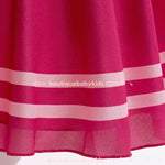 Detalhe da barra do vestido, com acabamento de faixas brancas sobre o tecido rosa, criando um efeito sofisticado.