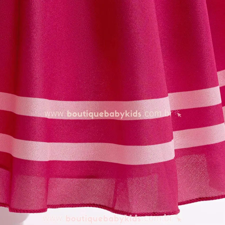 Detalhe da barra do vestido, com acabamento de faixas brancas sobre o tecido rosa, criando um efeito sofisticado.