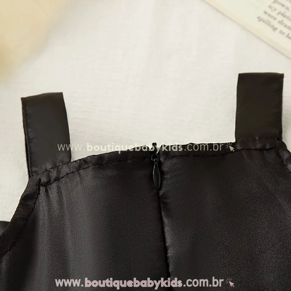 Fecho em zíper da parte de trás do vestido infantil com busto preto em tecido acetinado.