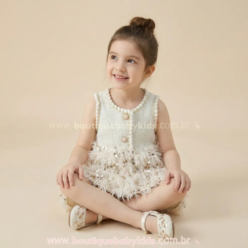 Criança sentada com as pernas cruzadas vestindo o modelo Belle Plume, mostrando o conforto do tecido e o volume divertido da saia de plumas para festas.