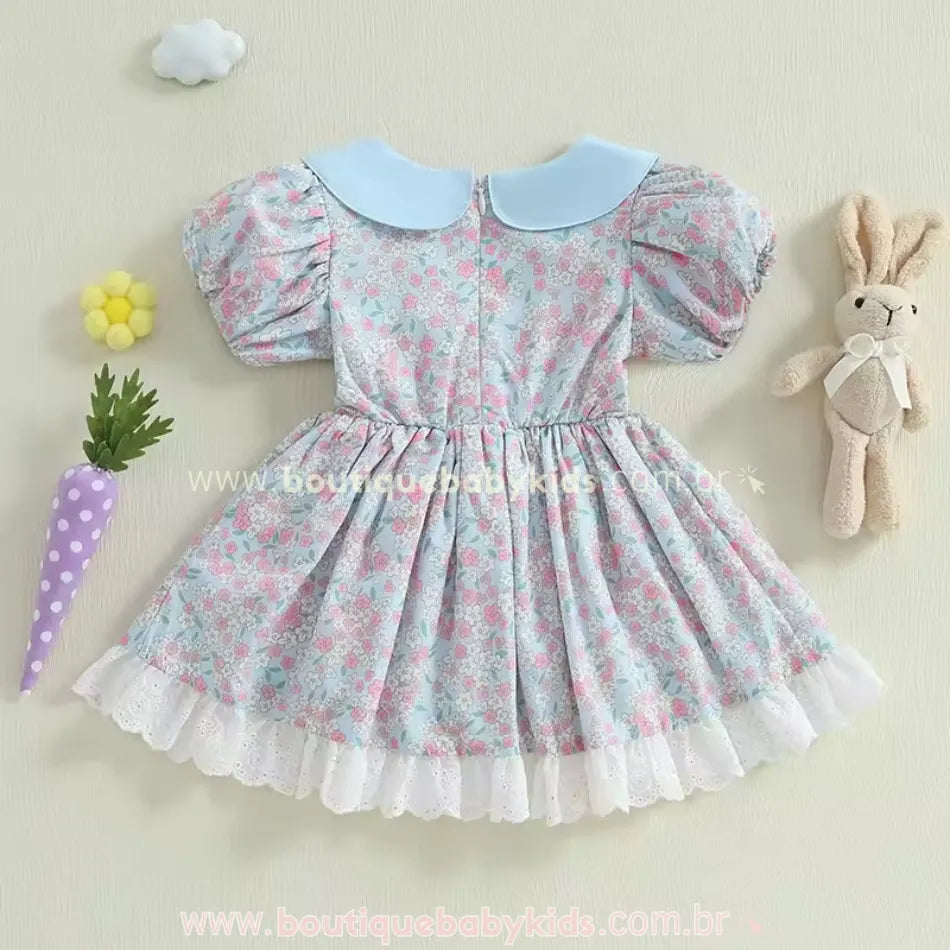 Parte traseira do vestido infantil azul floral com gola azul clara arredondada e fechamento por zíper, exibindo um acabamento delicado e franzido na cintura.