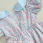 Fechamento traseiro do vestido, destacando a costura bem-acabada e a leveza do tecido floral azul com flores pequenas em rosa e branco.