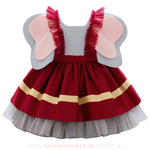 Vestido inspirado no elefante Dumbo visto de costas, com saia vermelha de detalhes dourados, camadas de tule cinza e grandes orelhas fixas nas alças de babado em tule vermelho.