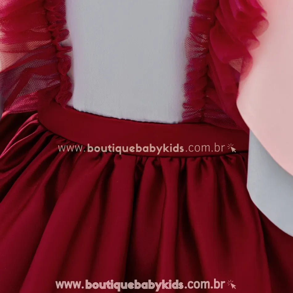 Detalhe da cintura e do caimento da saia vermelha com pregas suaves e acabamento refinado.