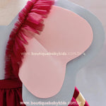 Close das orelhinhas fixas do vestido, feitas em camadas de tecido rosa e cinza para um efeito tridimensional.